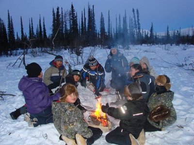 Kids sitting to a small fire.