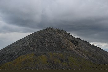 A jagged mountain top with some ominous looking clouds lurking above.