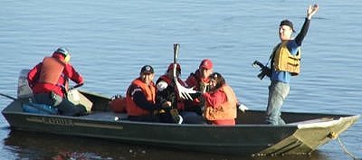Lindsay and Chris wave to the people on shore, as Shirley hold the torch with pride